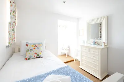a bedroom with a bed and a dresser and a mirror at Mansard House in Aldeburgh
