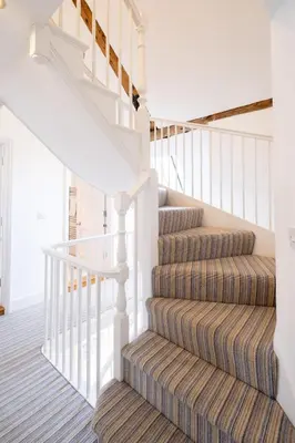 a carpeted staircase with white railings and a white stair case at Mansard House in Aldeburgh
