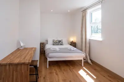 a bedroom with a bed and a desk and a window at Three Tuns Apartments - Hazel - Aldeburgh Coastal Cottages in Pettistree