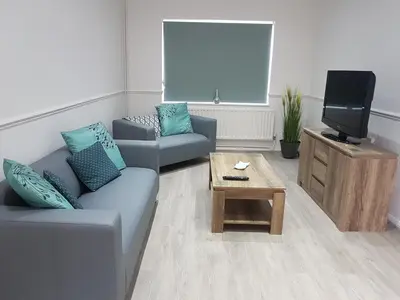 a living room with a couch and a tv at Rayleigh House in Rayleigh