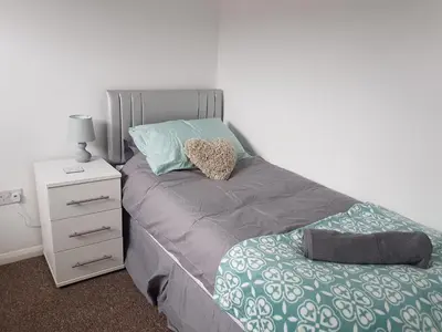 a bedroom with a bed and a nightstand with a heart pillow at Rayleigh House in Rayleigh