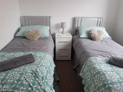 a bedroom with two twin beds and a night stand at Rayleigh House in Rayleigh