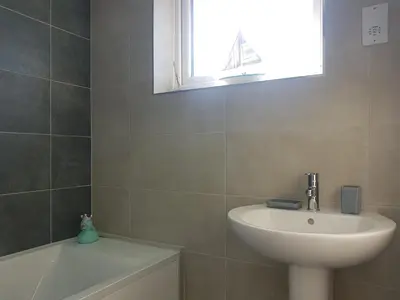 a bathroom with a sink and a tub and a window at Rayleigh House in Rayleigh