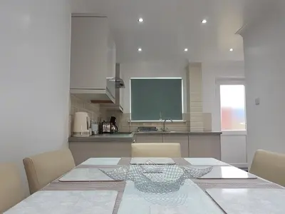 a dining room with a table and a kitchen at Rayleigh House in Rayleigh