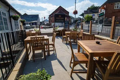 a row of wooden tables and chairs on a patio at Kings Arms Hotel in Stansted Mountfitchet
