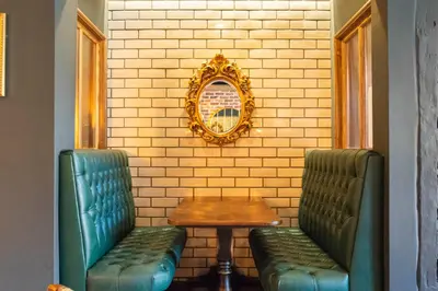 two green chairs and a table and a mirror at Kings Arms Hotel in Stansted Mountfitchet