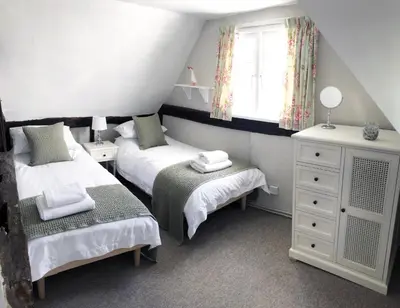 a small bedroom with two beds and a window at Millie's Cottage in Finchingfield