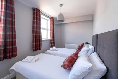 a bedroom with two beds and a window at Crags Nest in Aldeburgh