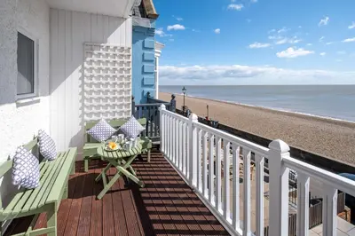 a balcony with a table and chairs and the beach at Crags Nest in Aldeburgh