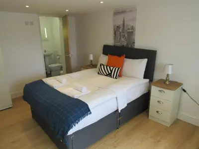 a bedroom with a large bed with orange and blue pillows at The Cambridge Suites - Tas Accommodations in Cambridge