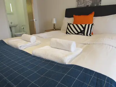 a large white bed with towels on it at The Cambridge Suites - Tas Accommodations in Cambridge