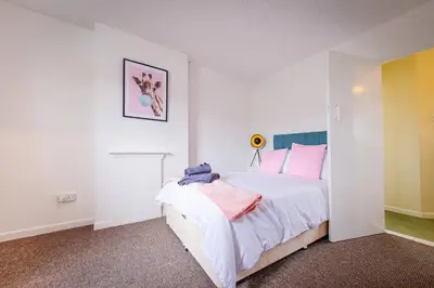 a bedroom with a large white bed with pink pillows at 4 Bed - 2 Baths 1 Walk In Shower Lots Of Parking in Ipswich