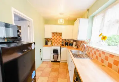 a kitchen with white cabinets and a black refrigerator at 4 Bed - 2 Baths 1 Walk In Shower Lots Of Parking in Ipswich