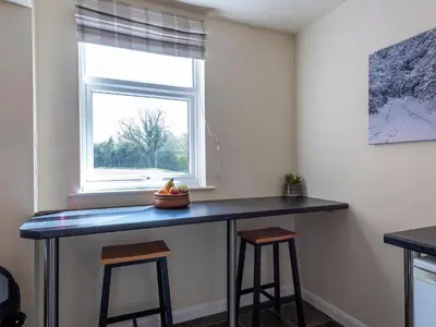 a counter in a room with a window and stools at Old Alton Hall Farmhouse in Tattingstone