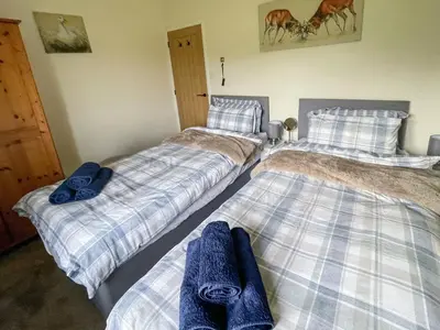 three beds in a room with blue towels on them at Old Alton Hall Farmhouse in Tattingstone