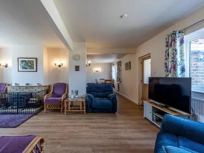 a living room with blue chairs and a flat screen tv at Old Alton Hall Farmhouse in Tattingstone