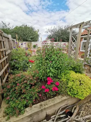 a garden with pink flowers in a wooden box at The Garden Room in Leiston