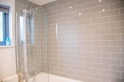 a bathroom with a shower and a bathtub with a glass door at 3 Oaks Court, Thorpeness in Thorpeness