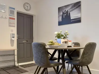 a dining room table with chairs and a clock on the wall at Hidden Gem in Willingham