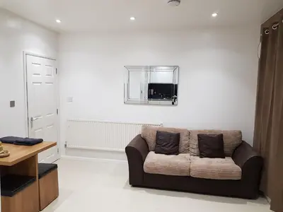 a living room with a brown couch and a mirror at Orwell Suite in Ipswich
