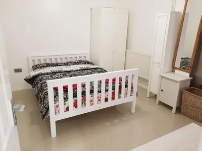 a white crib in a bedroom with a bed at Taj Suite in Ipswich