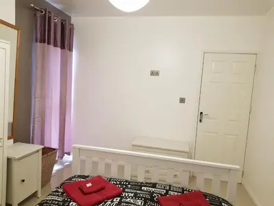a bedroom with a bed with two red towels on it at Taj Suite in Ipswich