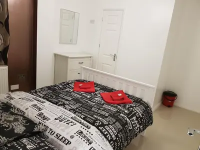 a bedroom with a bed with two red pillows on it at Taj Suite in Ipswich