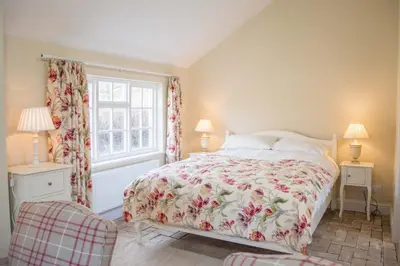 a bedroom with a bed with a floral bedspread and a window at Mill Cottage, Tunstall in Tunstall
