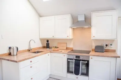 a white kitchen with white cabinets and a sink at Mill Cottage, Tunstall in Tunstall