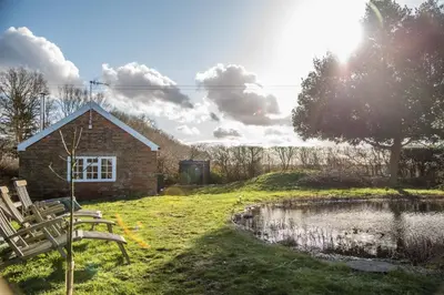 a house with two chairs next to a pond at Mill Cottage, Tunstall in Tunstall