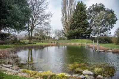 a pond in the middle of a park with trees at Mill Cottage, Tunstall in Tunstall