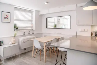 a white kitchen with a wooden table and chairs at Sutton House, Woodbridge in Woodbridge