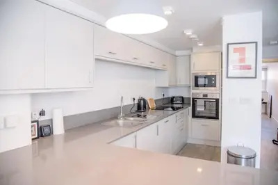 a white kitchen with white cabinets and appliances at Sutton House, Woodbridge in Woodbridge