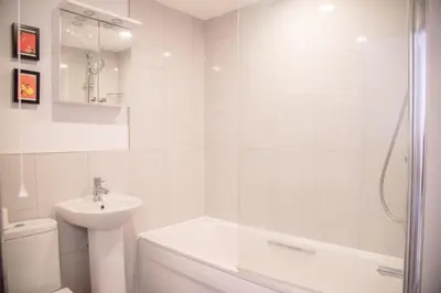 a white bathroom with a sink and a shower at Sutton House, Woodbridge in Woodbridge