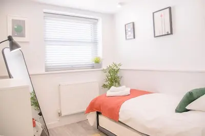 a white bedroom with a bed and a window at Sutton House, Woodbridge in Woodbridge