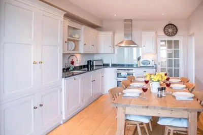 a white kitchen with a wooden table and chairs at Tower House, Aldeburgh in Aldeburgh