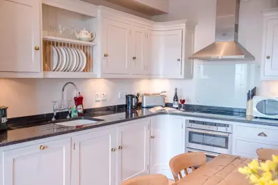 a white kitchen with white cabinets and a table at Tower House, Aldeburgh in Aldeburgh