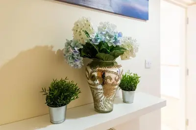 a vase filled with flowers sitting on a shelf at 1-bedroom apartment with balcony, Hoddesdon in Hoddesdon