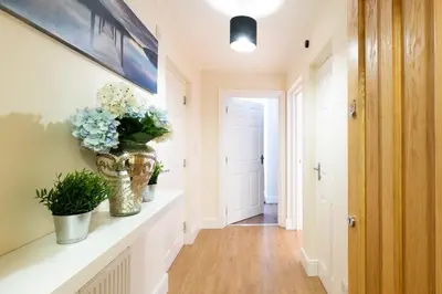 a hallway with a vase of flowers on a counter at 1-bedroom apartment with balcony, Hoddesdon in Hoddesdon