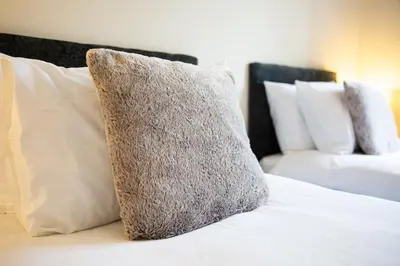 a pillow on a bed with pillows and a couch at 1-bedroom apartment with balcony, Hoddesdon in Hoddesdon