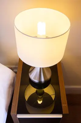 a lamp on a glass table with a white lamp at 1-bedroom apartment with balcony, Hoddesdon in Hoddesdon