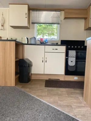 a kitchen with white cabinets and a black appliance at KellysHolidayHomes Atlas 3 bedrooms caravan in Weeley