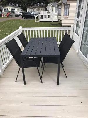 a black picnic table and two chairs on a porch at KellysHolidayHomes Atlas 3 bedrooms caravan in Weeley