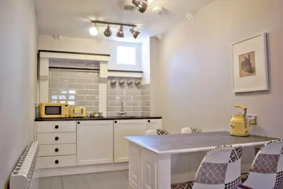 a kitchen with white cabinets and a table and chairs at City Studios in Ely