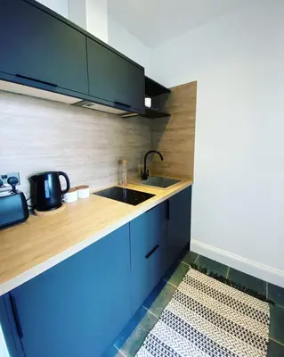 a kitchen with blue cabinets and a sink at Cuckoo Rooms in Colchester