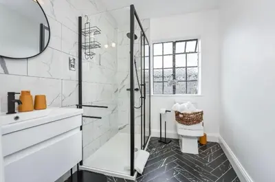 a white bathroom with a shower and a sink at Cuckoo Rooms in Colchester