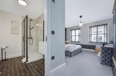 a bedroom with a bed and a bathroom with a tub at Cuckoo Rooms in Colchester