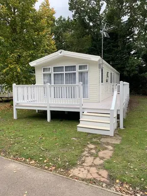 a white house with a porch and a white fence at Kellys Holiday Homes 24 Willerby 2 bedrooms caravan in Weeley