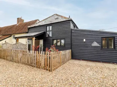 a black house with a fence in front of it at The Cart Lodge in Halstead