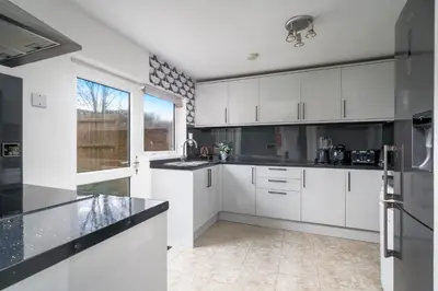 a kitchen with white cabinets and a large window at Skyvillion-STEVENAGE Amazing 3Bed House, Garden, Free Off Street Parking for 2 Cars, WiFi in Stevenage